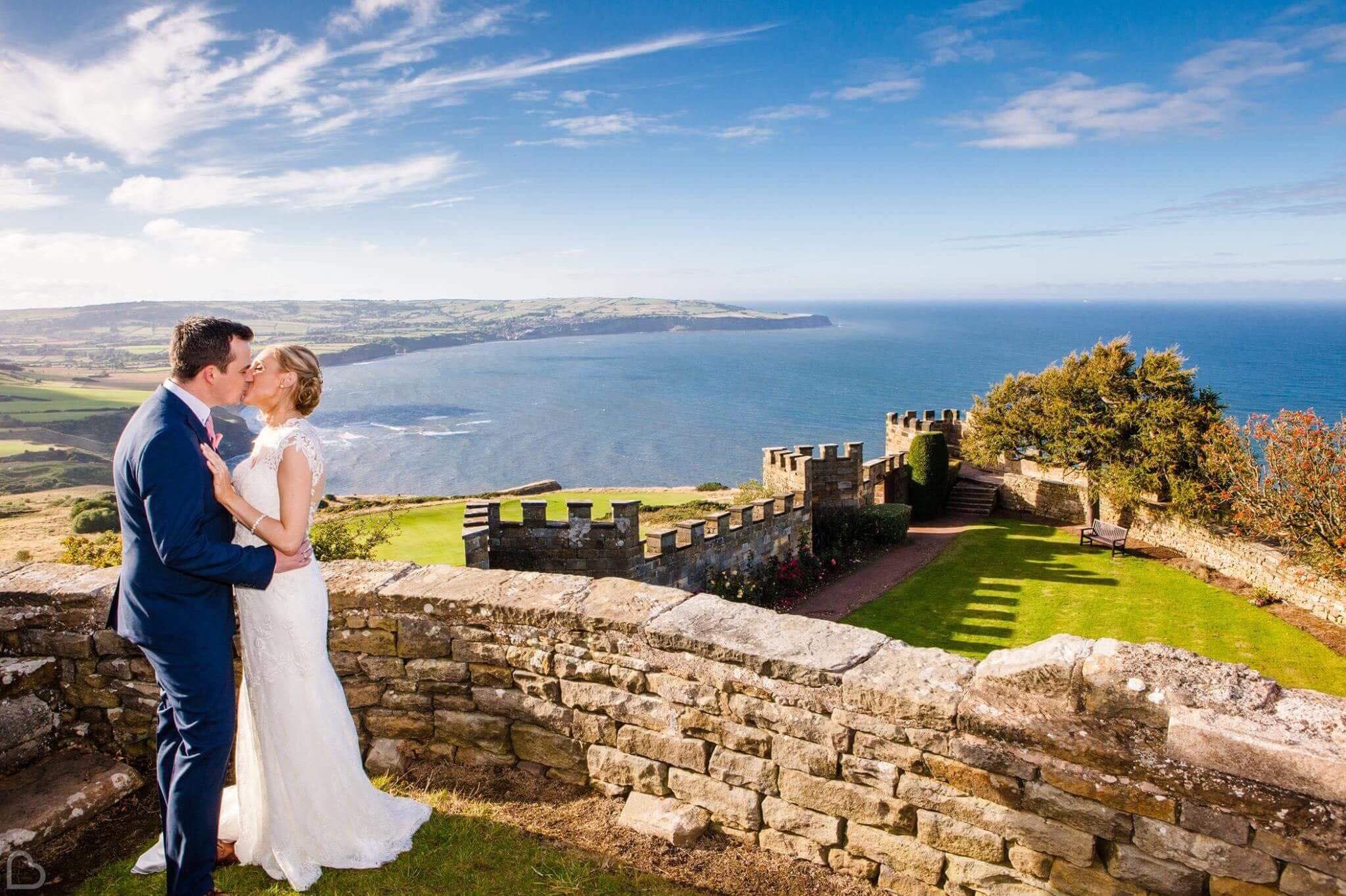 newlyweds kiss with the sea behind them at raven hall 