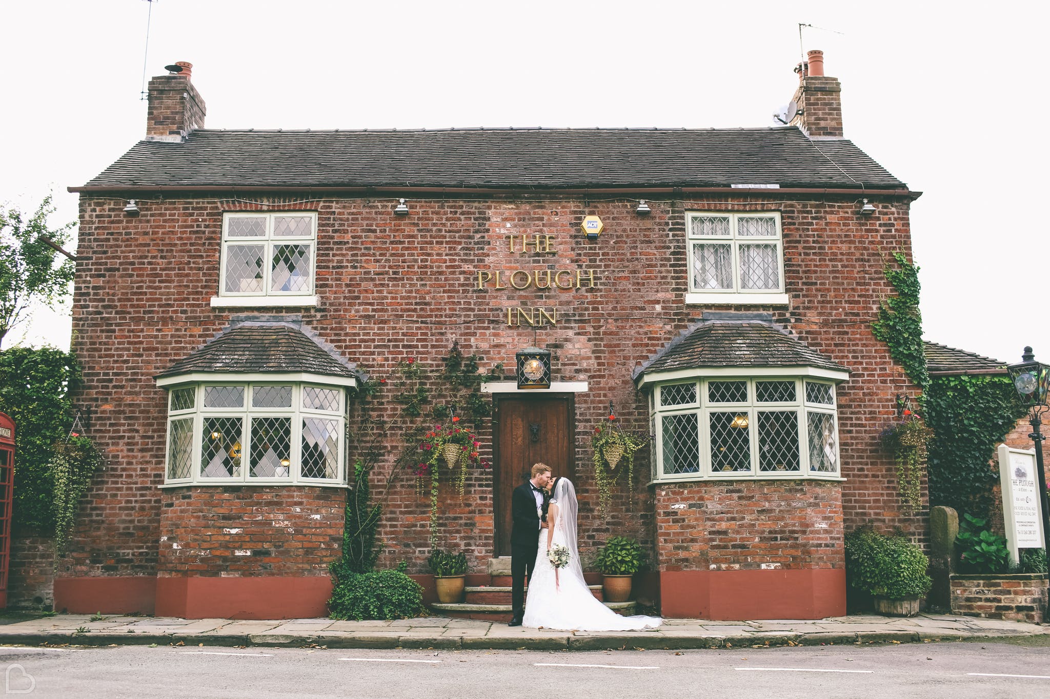a couple kisses outside the plough inn a budget wedding venue in the uk 