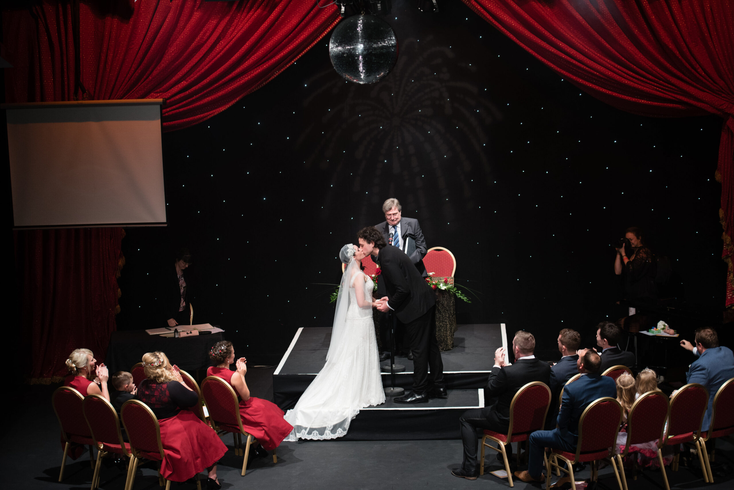 Bridebook.co.uk bride and groom kiss on stage