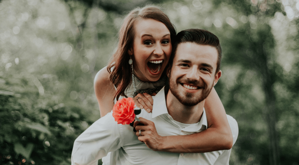 a newly engaged couple looks happy at the camera!