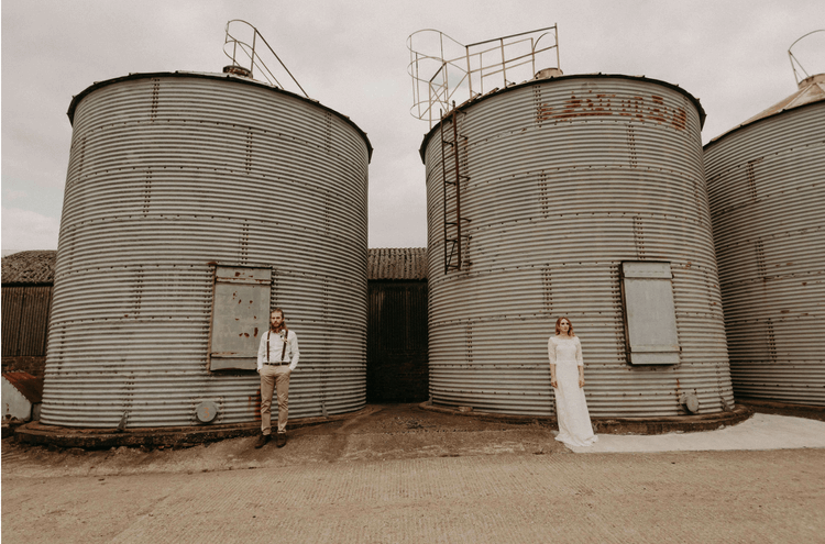 Bridebook.co.uk alternative bride and groom in front of silos