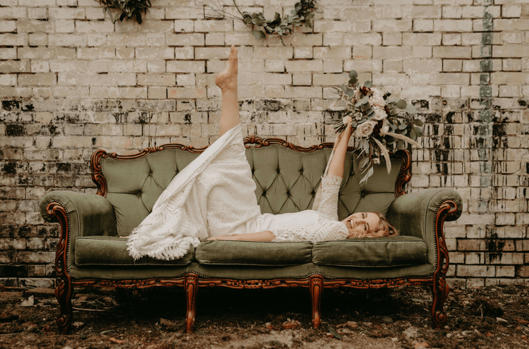 Bridebook.co.uk bride lying on soda in front of distressed brick wall
