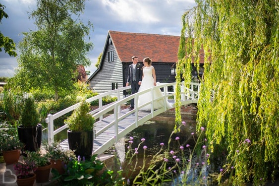 The High House wedding venue, a married couple walk over a small white bridge in Essex