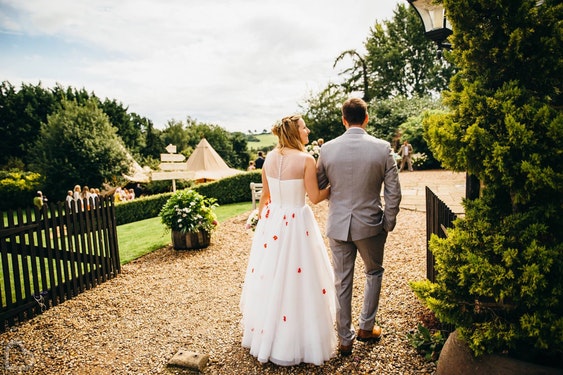 Married couple walk around Lodge Farm House, an outdoor wedding venue in Hertfordshire