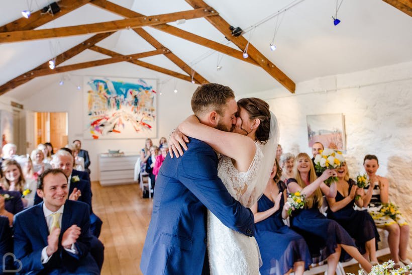 A newly married couple kisses in Monks Withecombe, a barn wedding venue in Devon