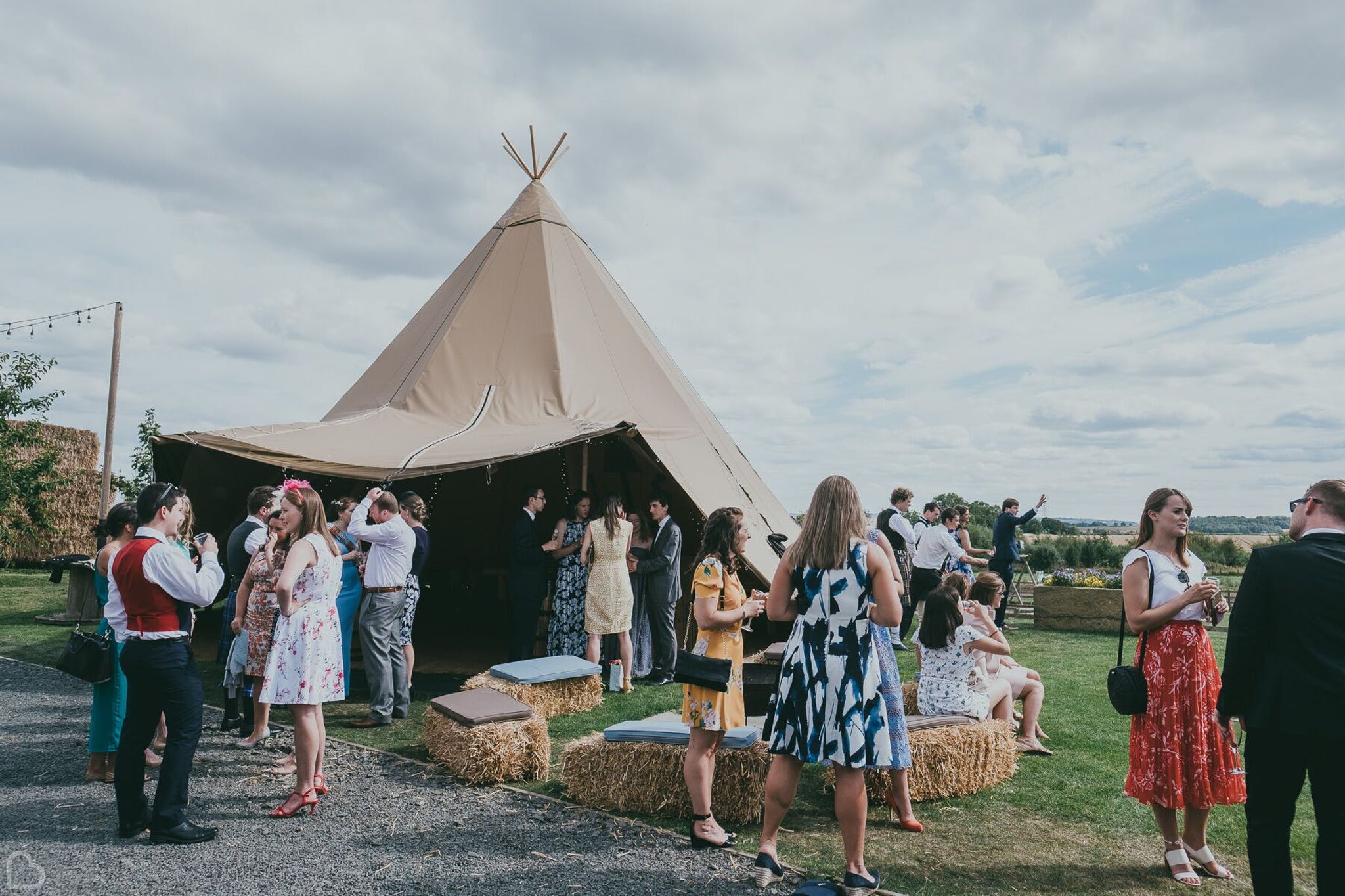 wedding guests relaxing in from of teepee at vallum farm wedding venue