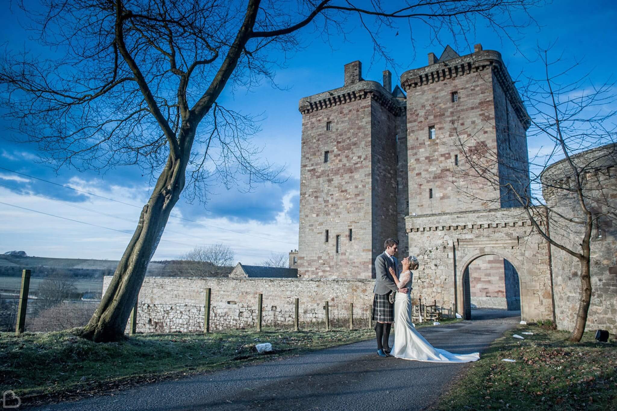 newlyweds pose in front of borthwick castle
