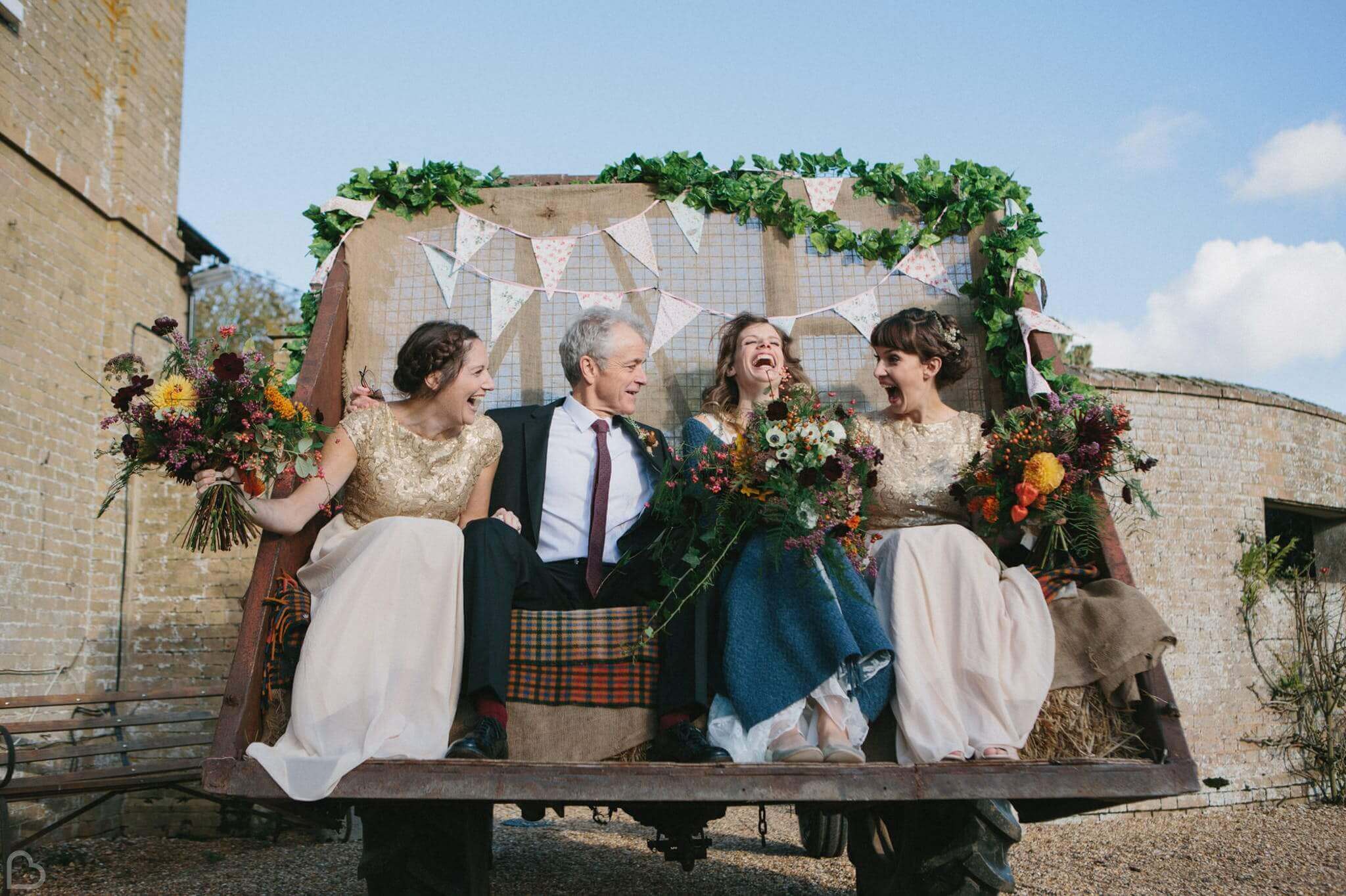 wedding guests laugh at the back of a truck in godwich great hall barn