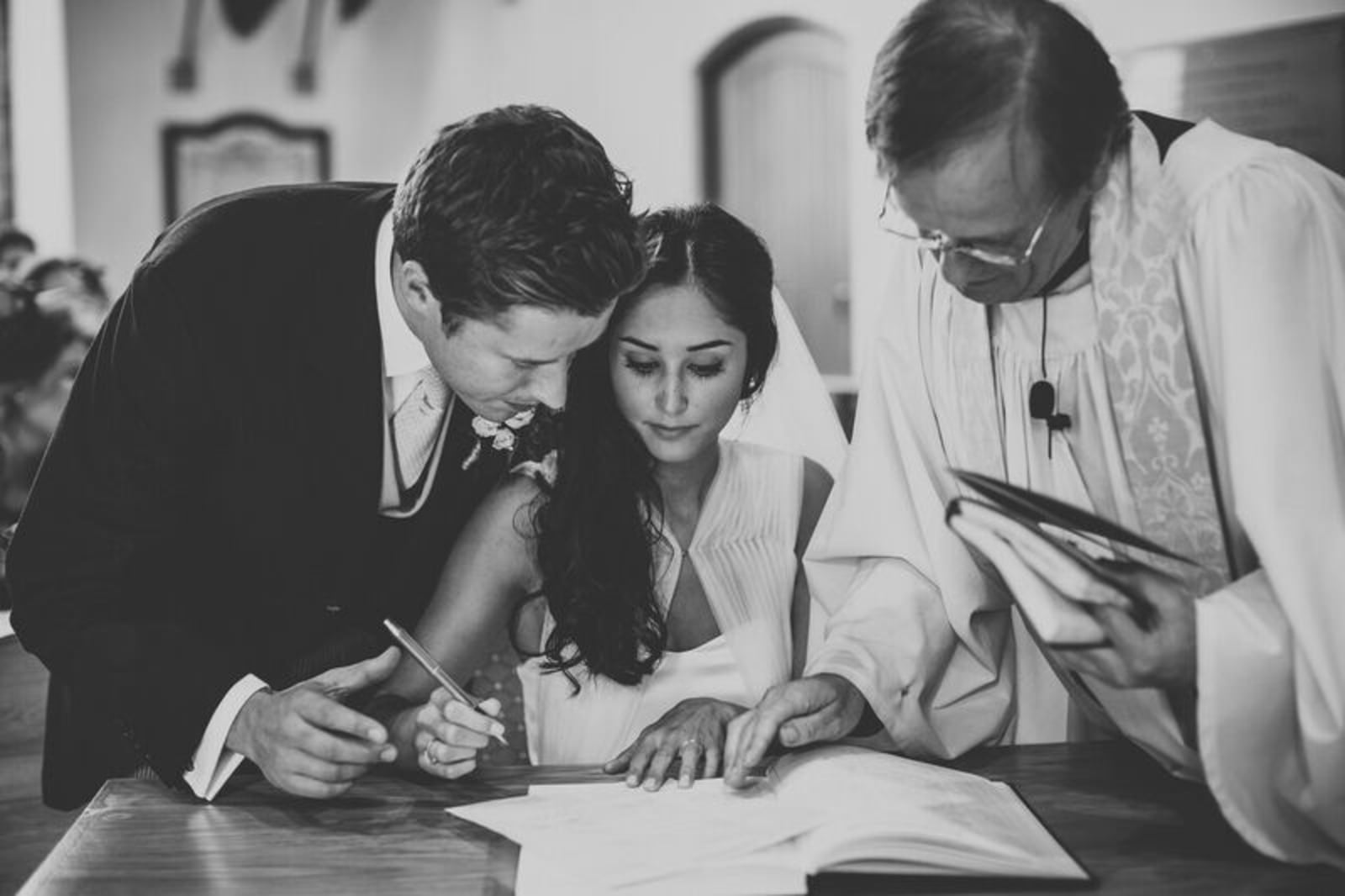 Bridebook.co.uk- bride and groom signing the register with the priest 
