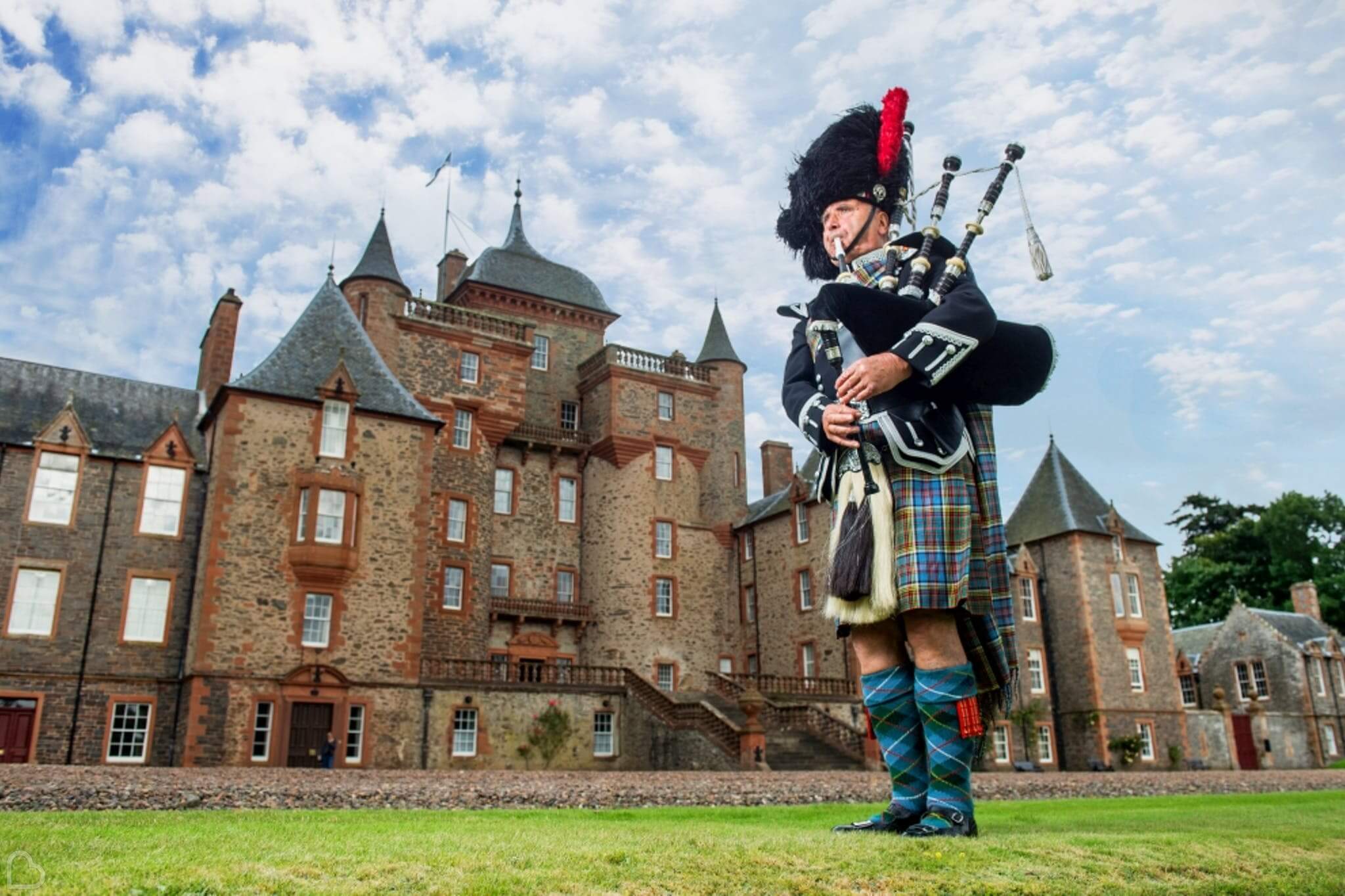 a scottish man plays the pipes in front of thirslestane castle 
